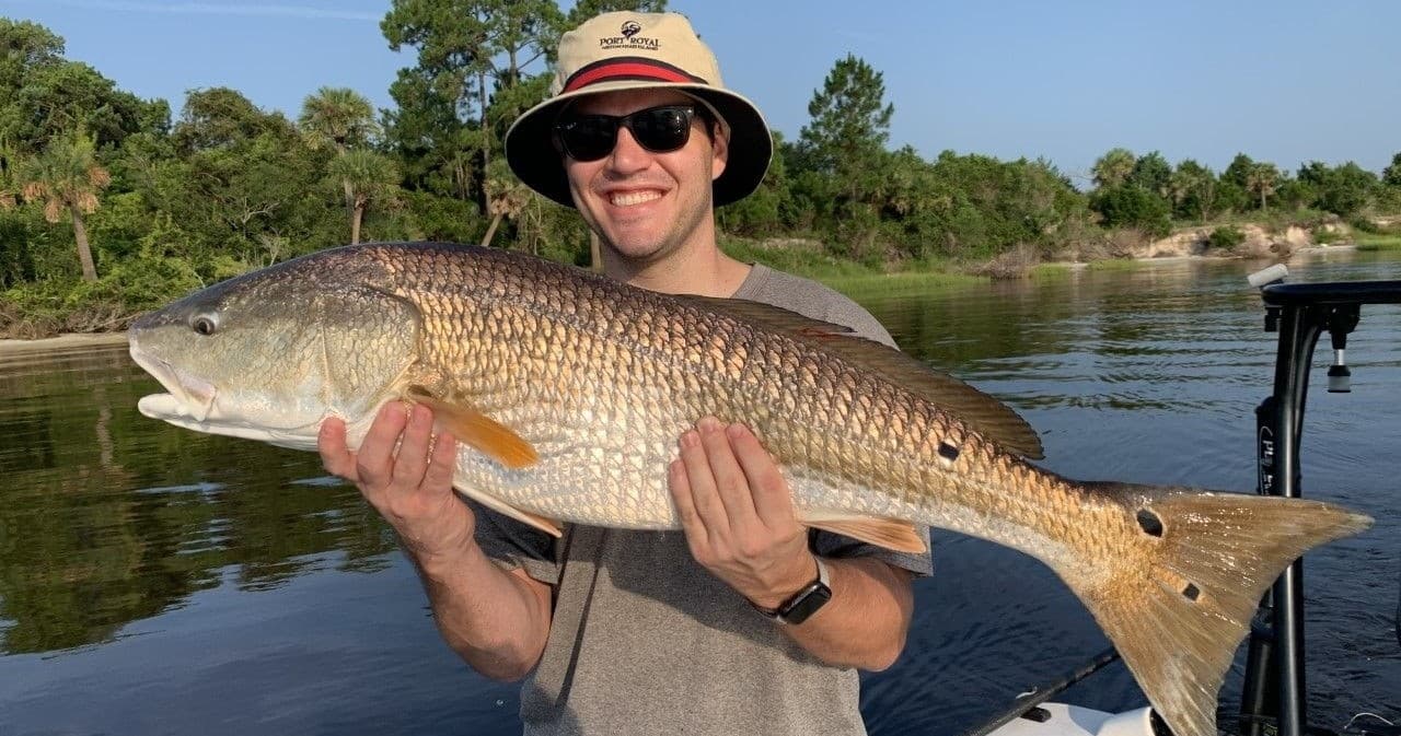 Angler holding large redfish on North Florida marsh boat
