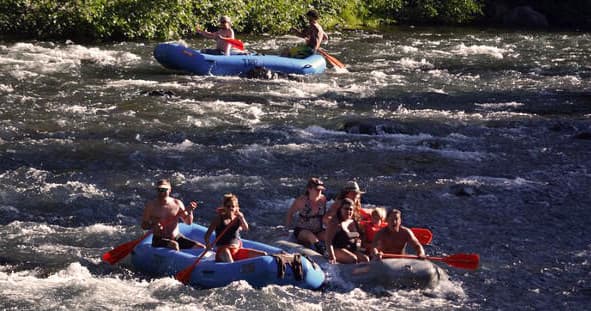 Rafters running whitewater rapids on scenic mountain river