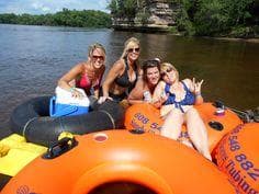 Group tubing down river on inflatable rafts, outdoor water fun