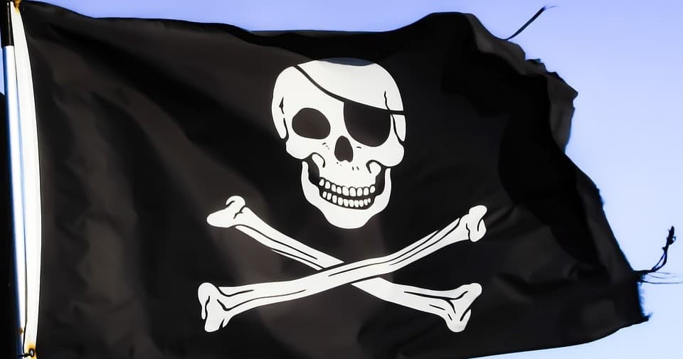 Black pirate Jolly Roger flag flying outdoors, nautical theme