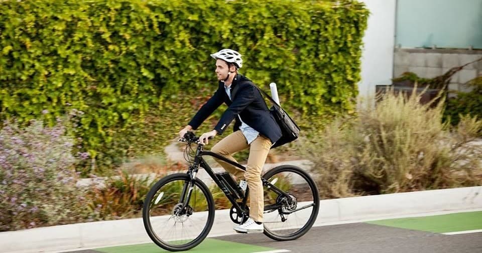 Cyclist commuting on tree-lined bike lane in urban neighborhood