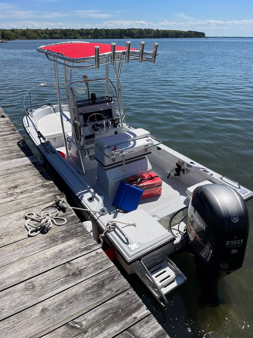 Center console fishing boat docked on calm lake, outboard engine