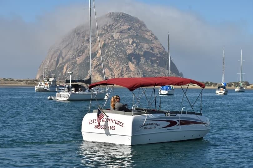 Chartered sailboat cruising near coastal rock landmark at harbor