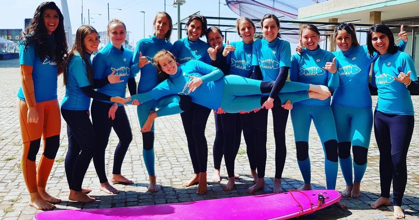 Female surf students posing with colorful board on seaside promenade