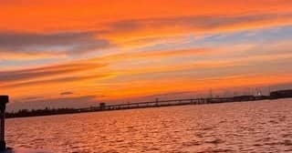 Vibrant sunset over coastal skyline with calm bay waters, evening