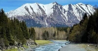 Mountain river valley with snow peaks and trail in Alaska