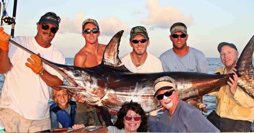 Group anglers posing with giant marlin after deep-sea catch