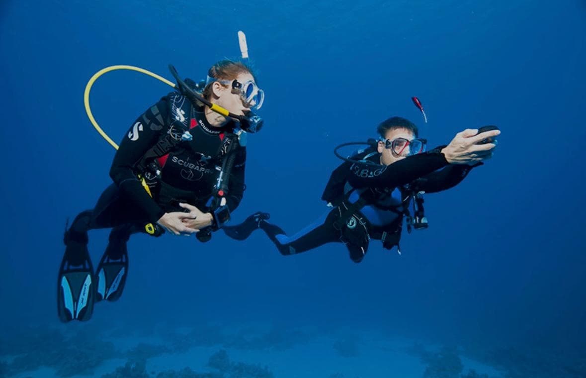 Two scuba divers silhouetted in deep blue open water