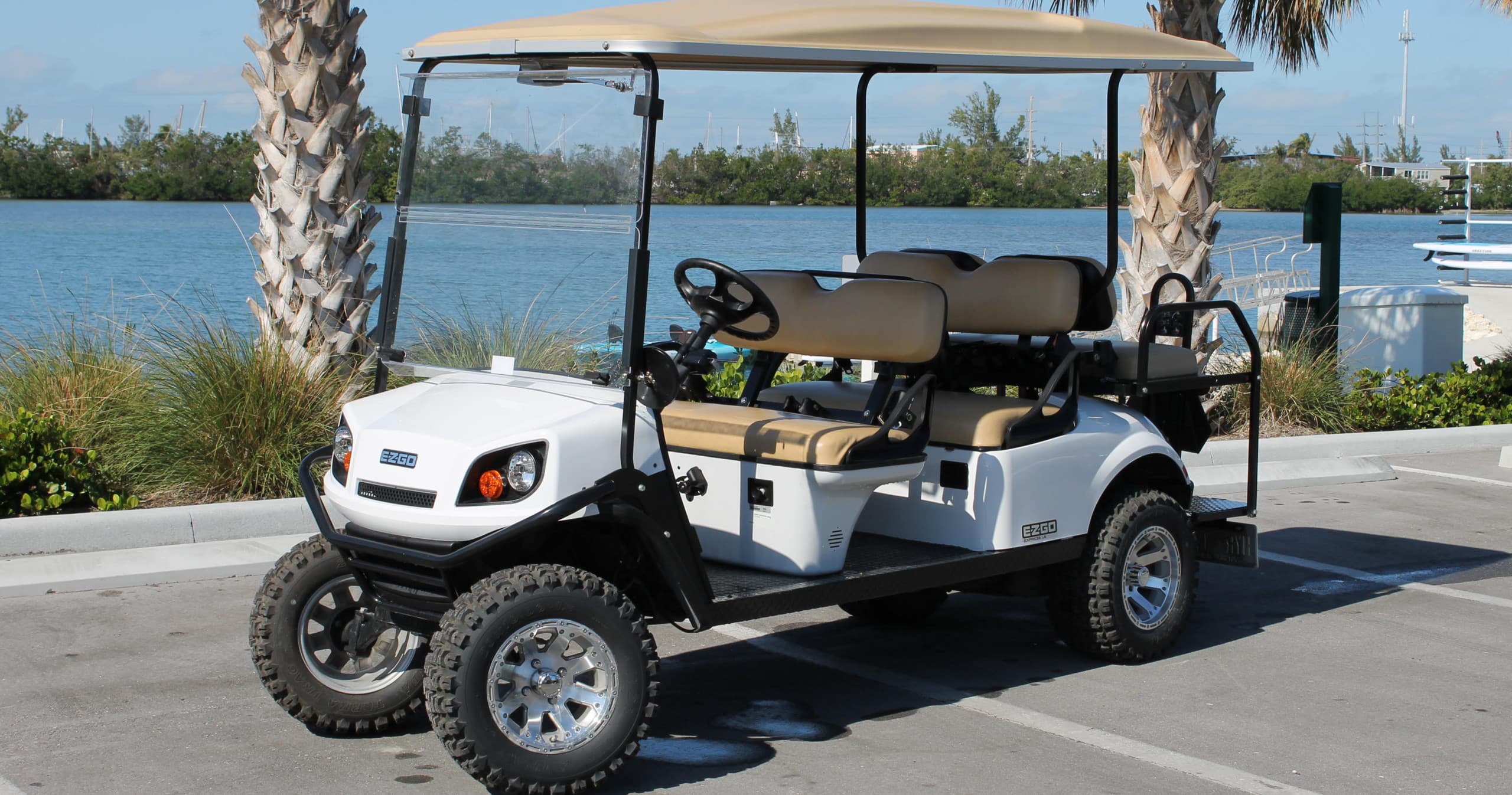 White golf cart parked by waterfront with palm trees in Key West