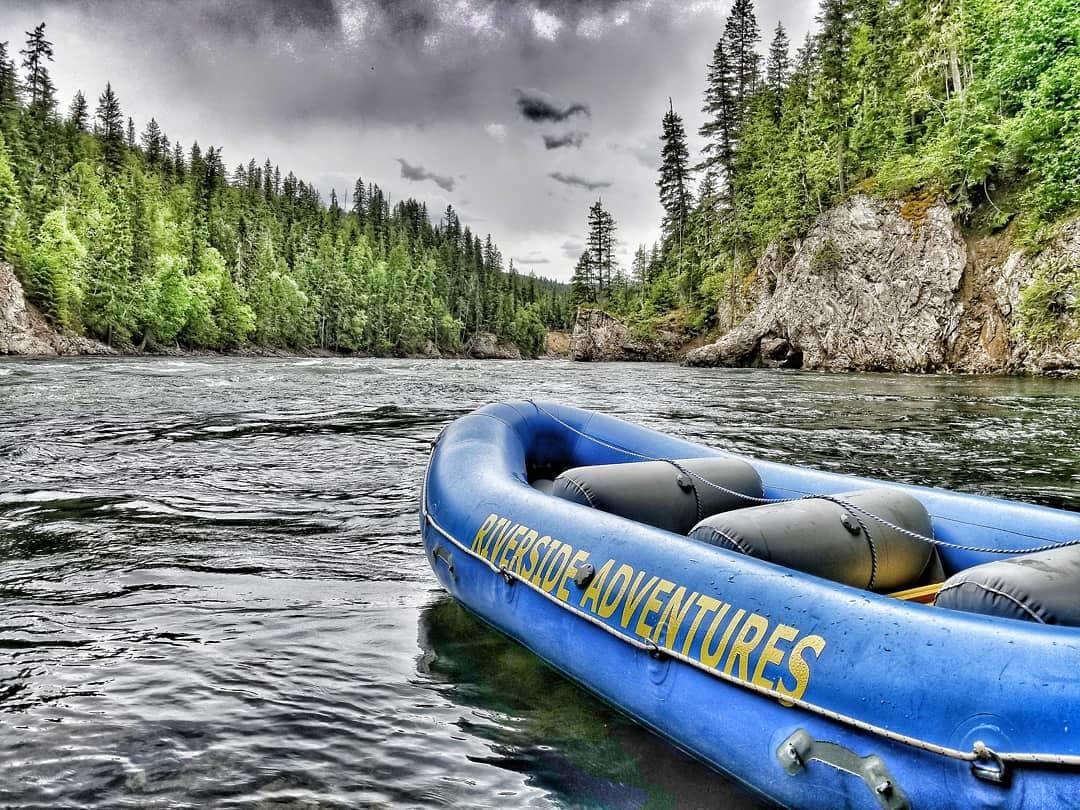 Blue raft floating on river with dramatic rocky canyon walls
