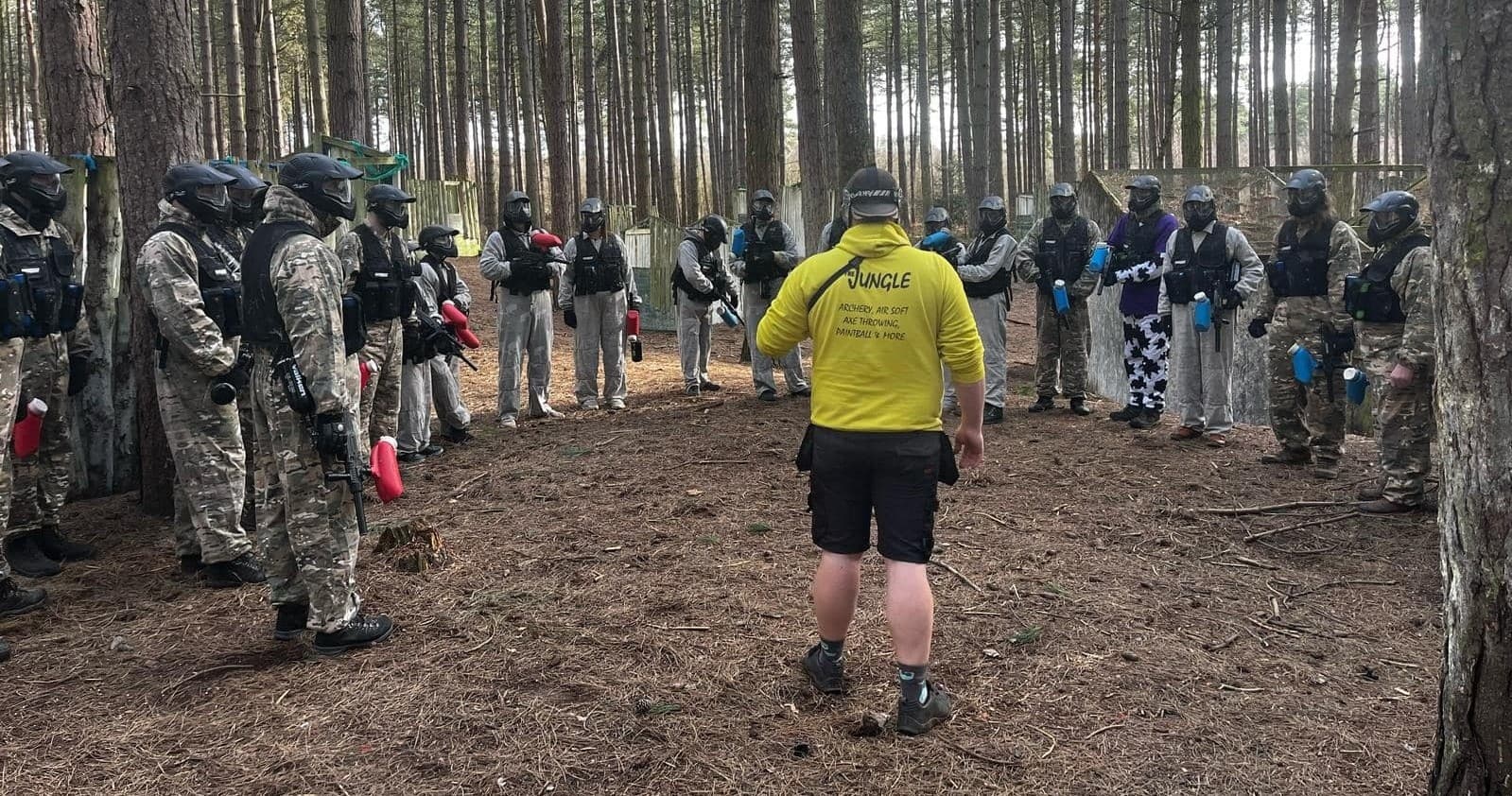 Instructor briefing paintball team in wooded outdoor training circle