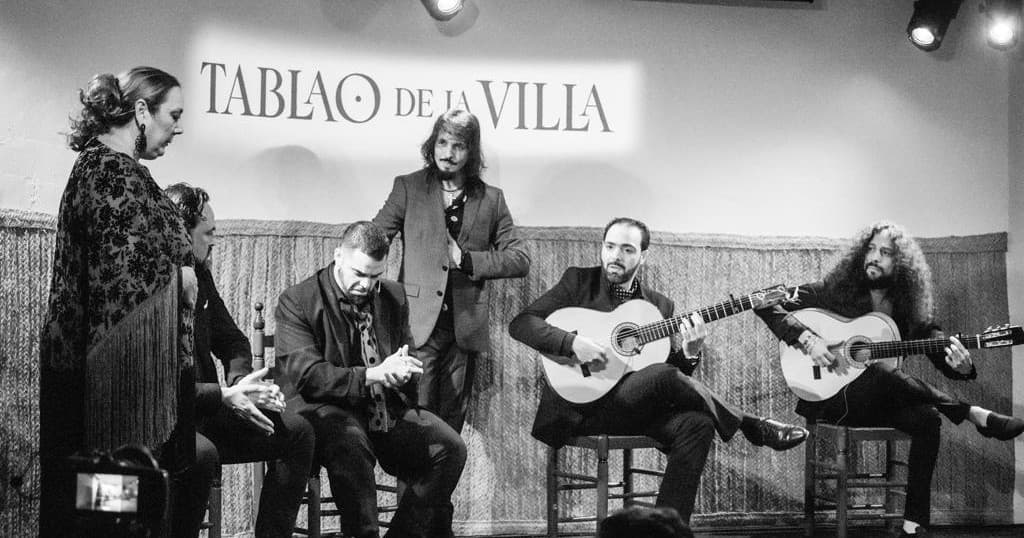 Black-and-white flamenco ensemble performing on tablao stage