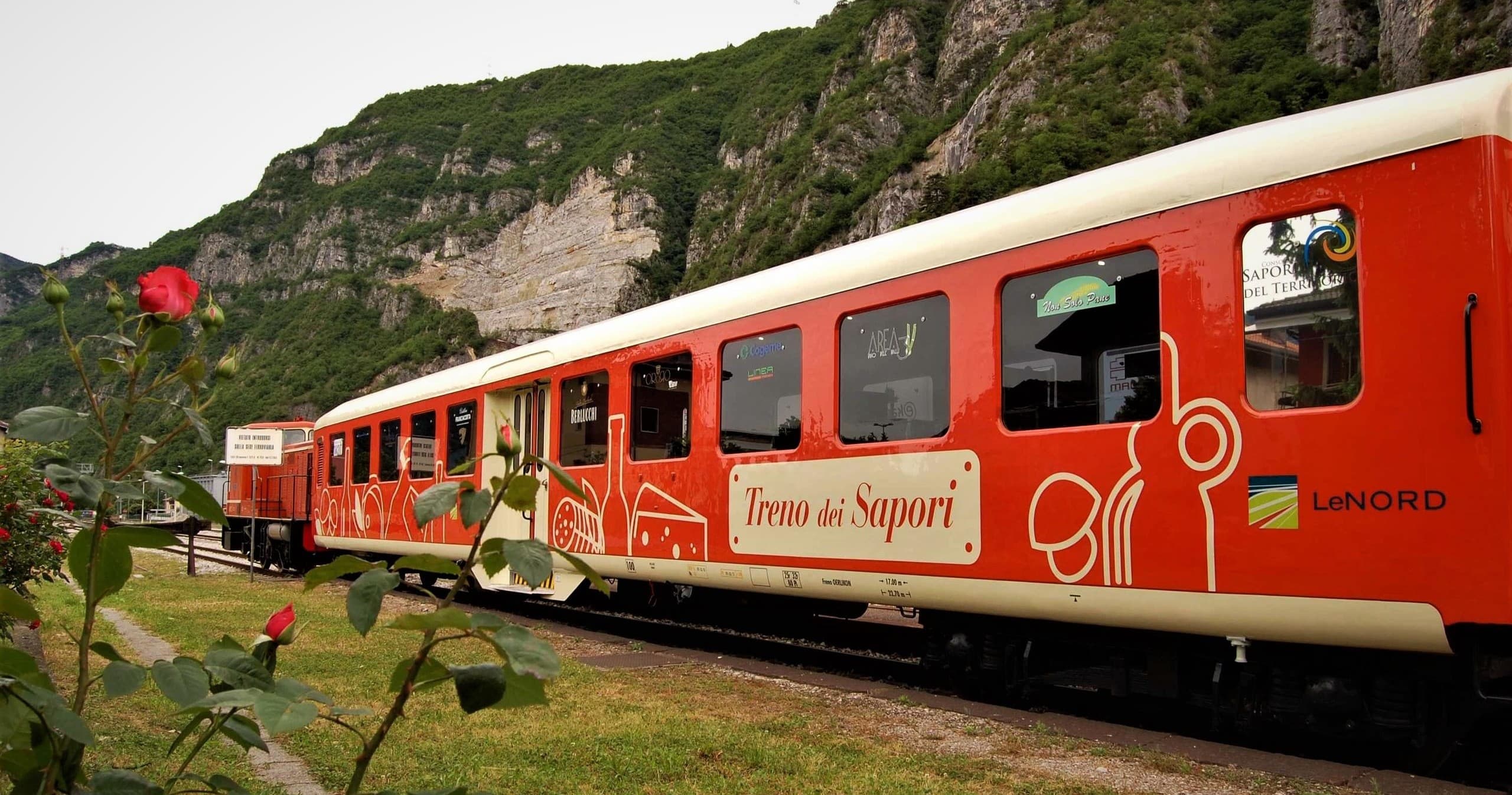 Red scenic train passing mountain vineyards, panoramic ride