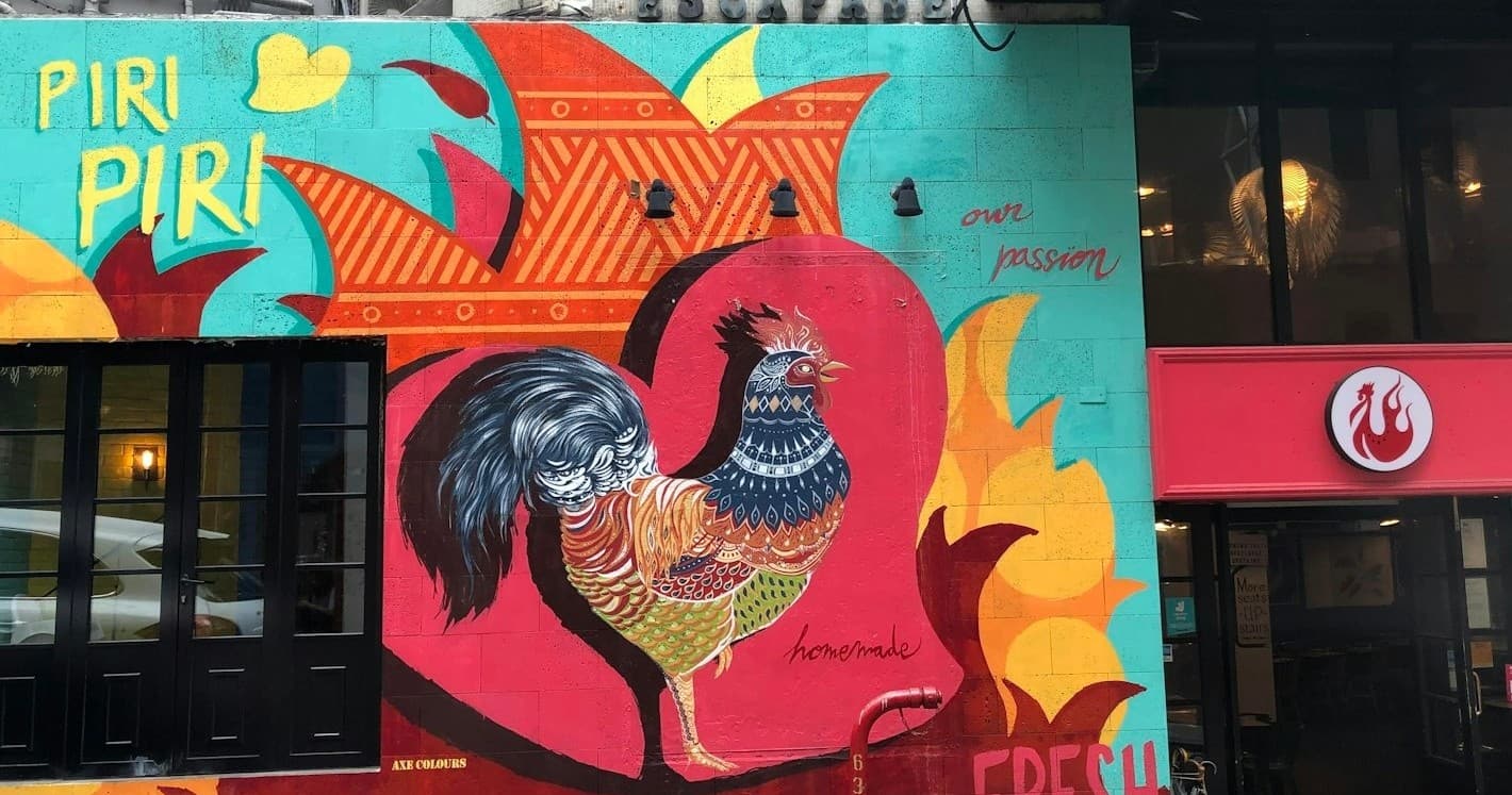 Colorful rooster street mural on Lisbon building, urban stroll
