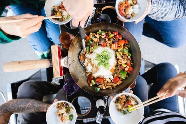 Friends sharing communal street-food bowl outdoors