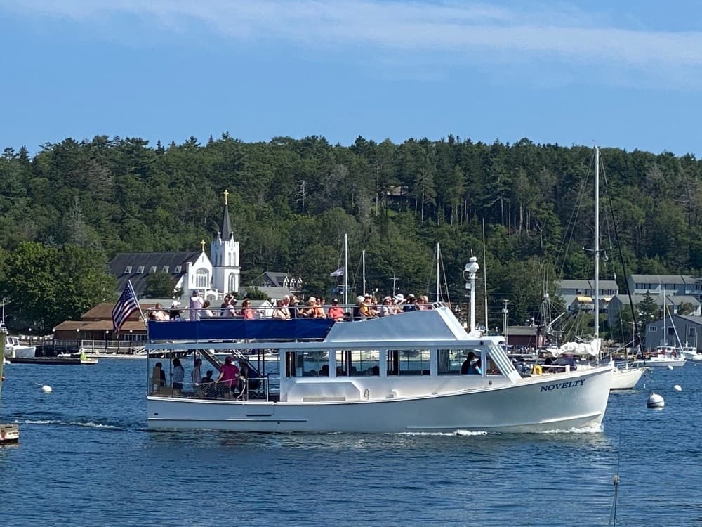 Harbor cruise boat passing seaside town, coastal sightseeing