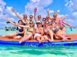 Group relaxing on floating mat over turquoise shallow bay