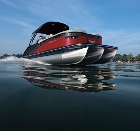 Red luxury pontoon cutting through calm lake waters at sunrise