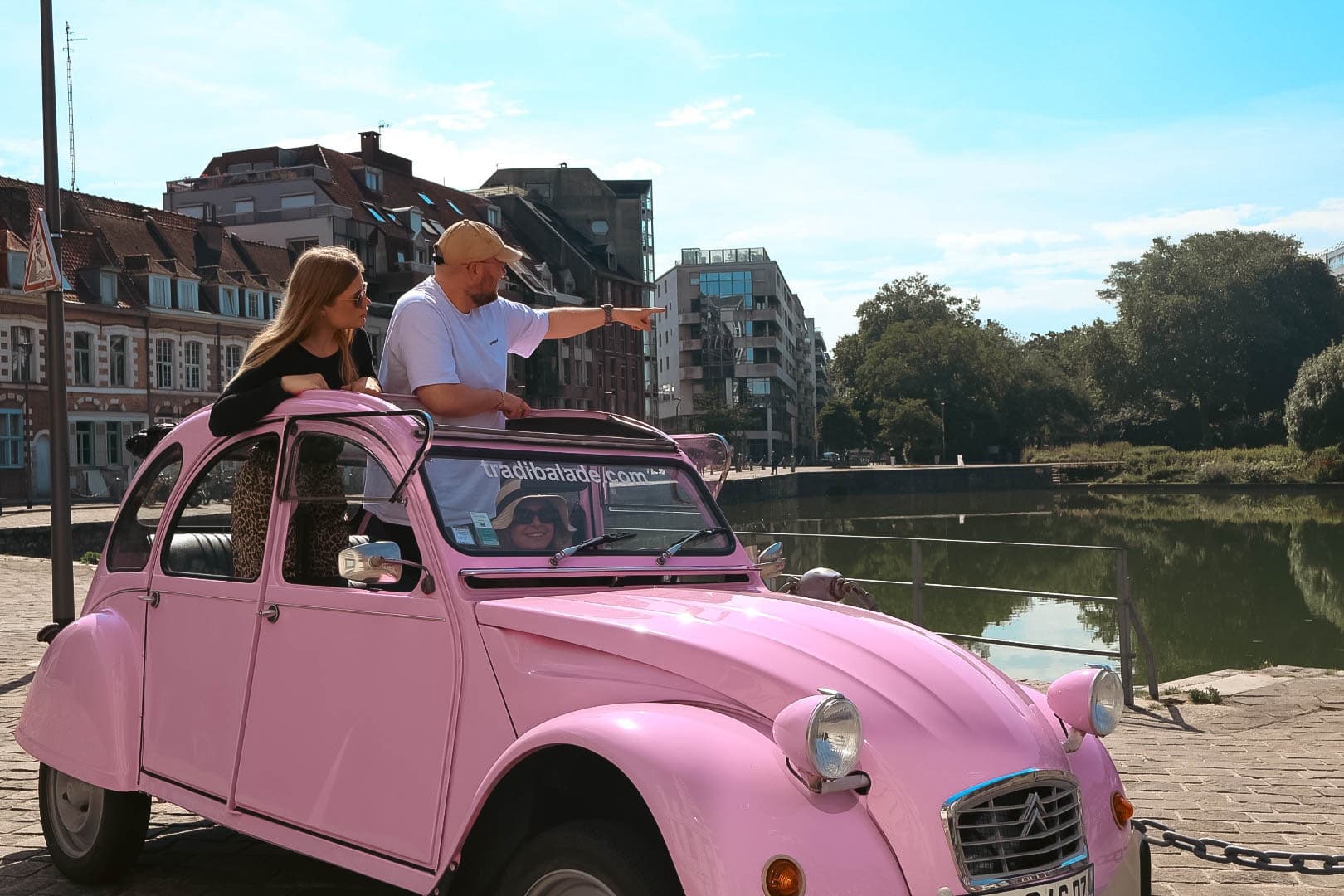 Couple in pink 2CV convertible by riverside, romantic scenic drive