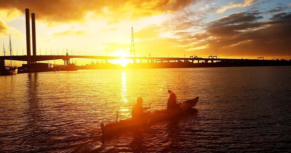 Sunrise kayaking near Melbourne bridge silhouetted paddlers