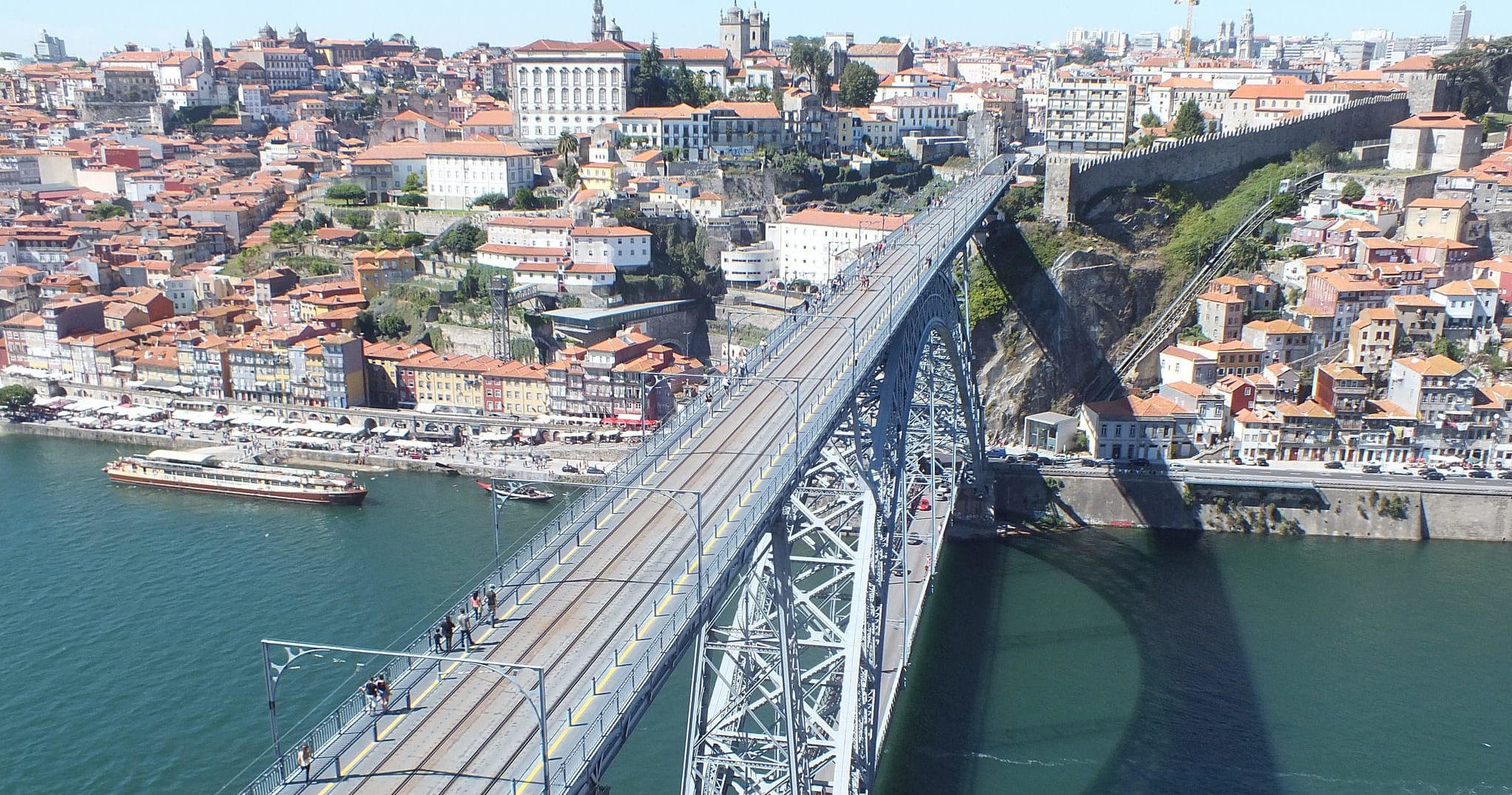 High-angle view of metal arch bridge crossing urban river in Porto