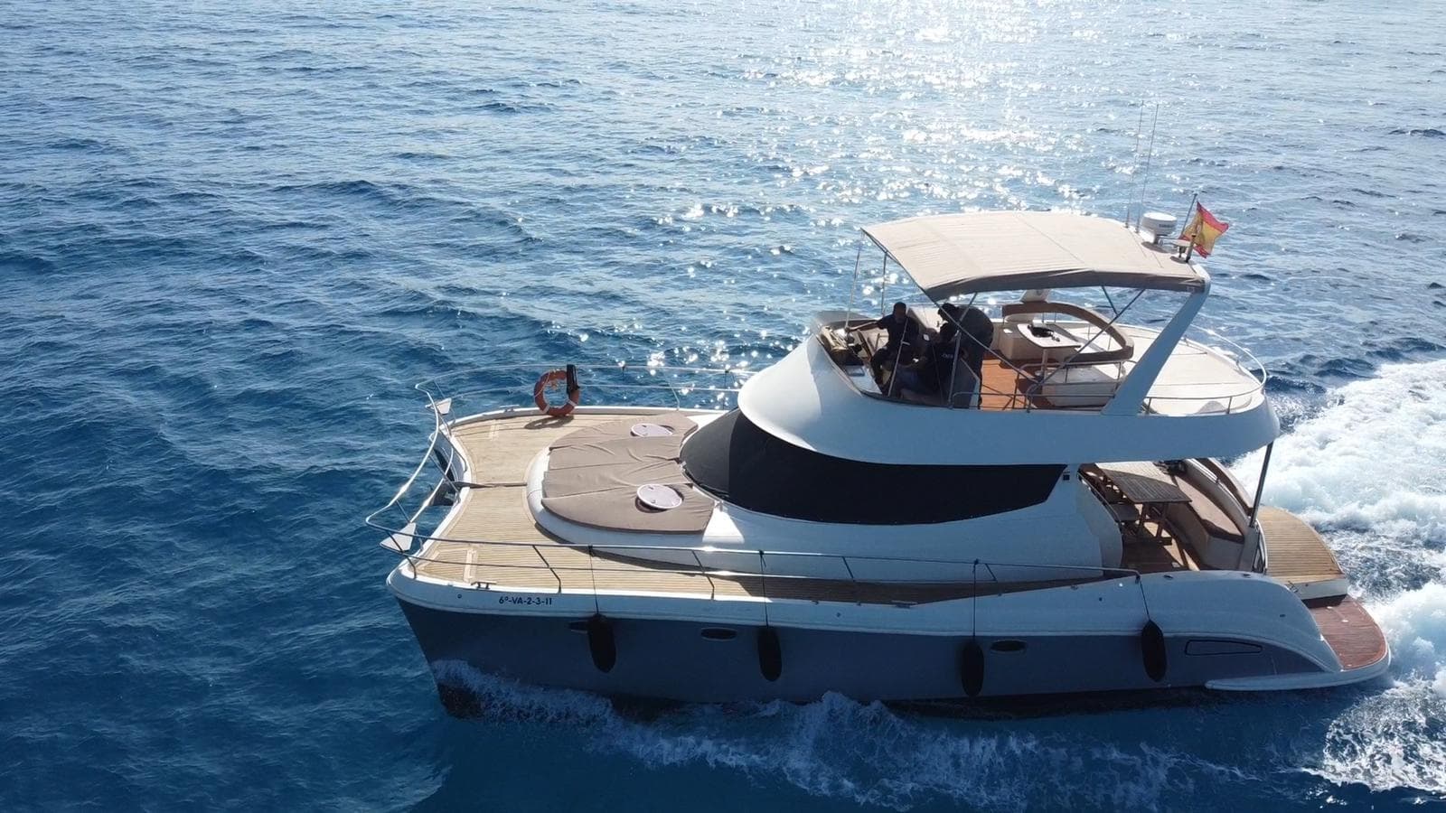 Yacht sailing on calm blue sea near volcanic Lanzarote coastline