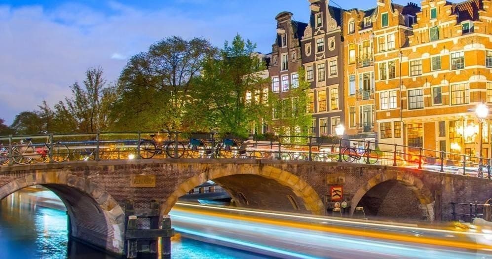 Scenic Amsterdam canal bridge with evening light trails