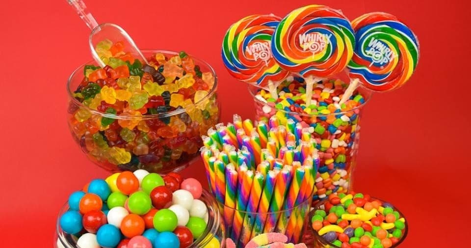 Colorful lollipops and jarred candies on red shop display