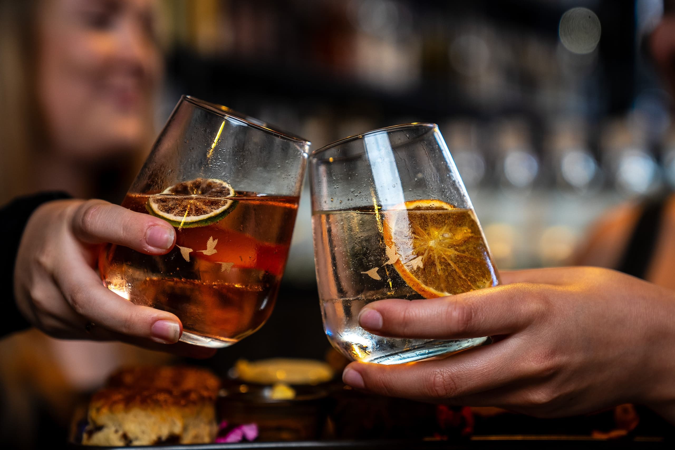 Friends clinking cocktails at cozy pub bar celebrating