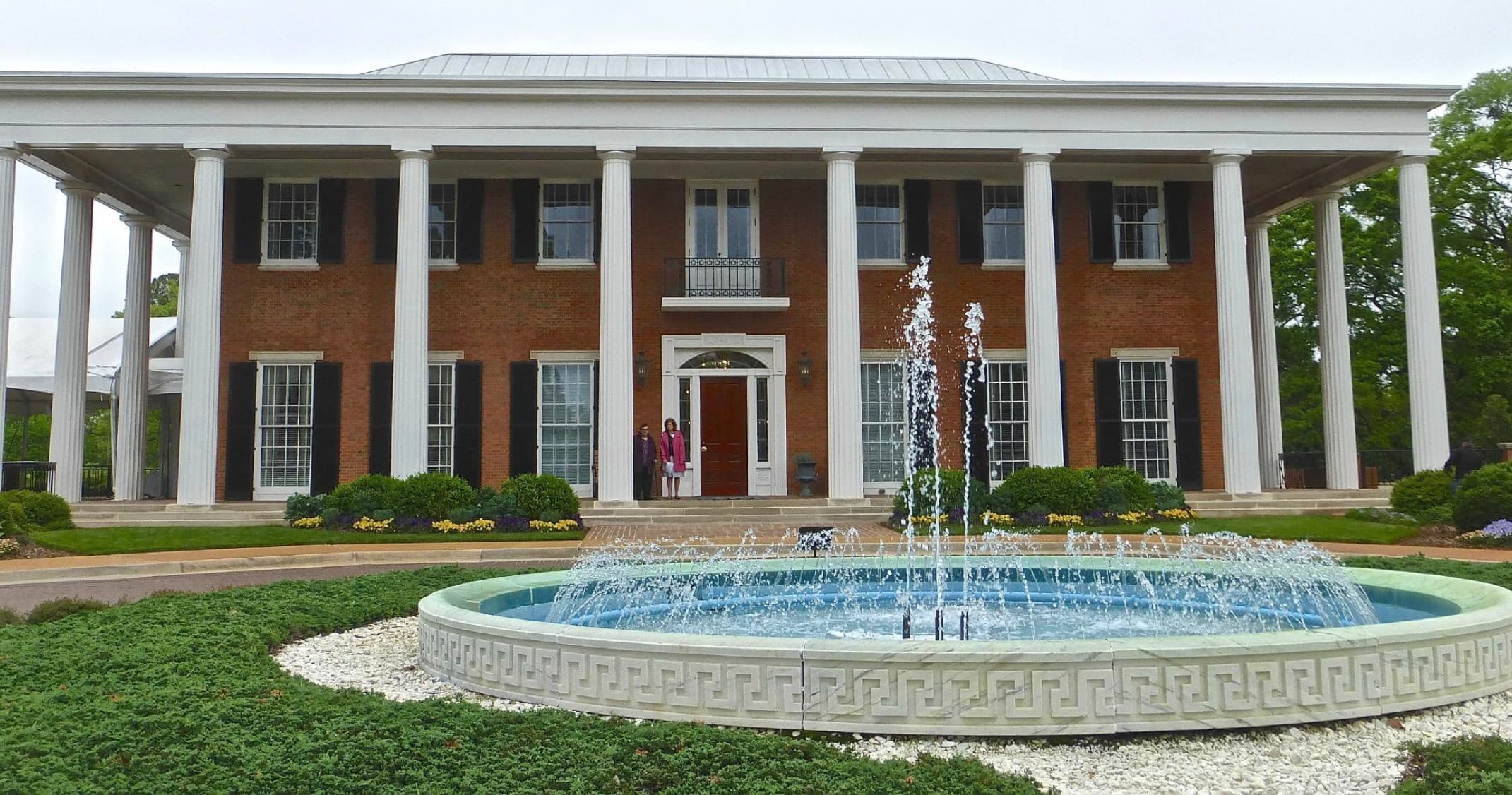 Historic mansion facade with fountain in landscaped grounds