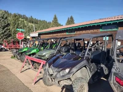 Off-road UTVs parked at rental staging area by mountain road