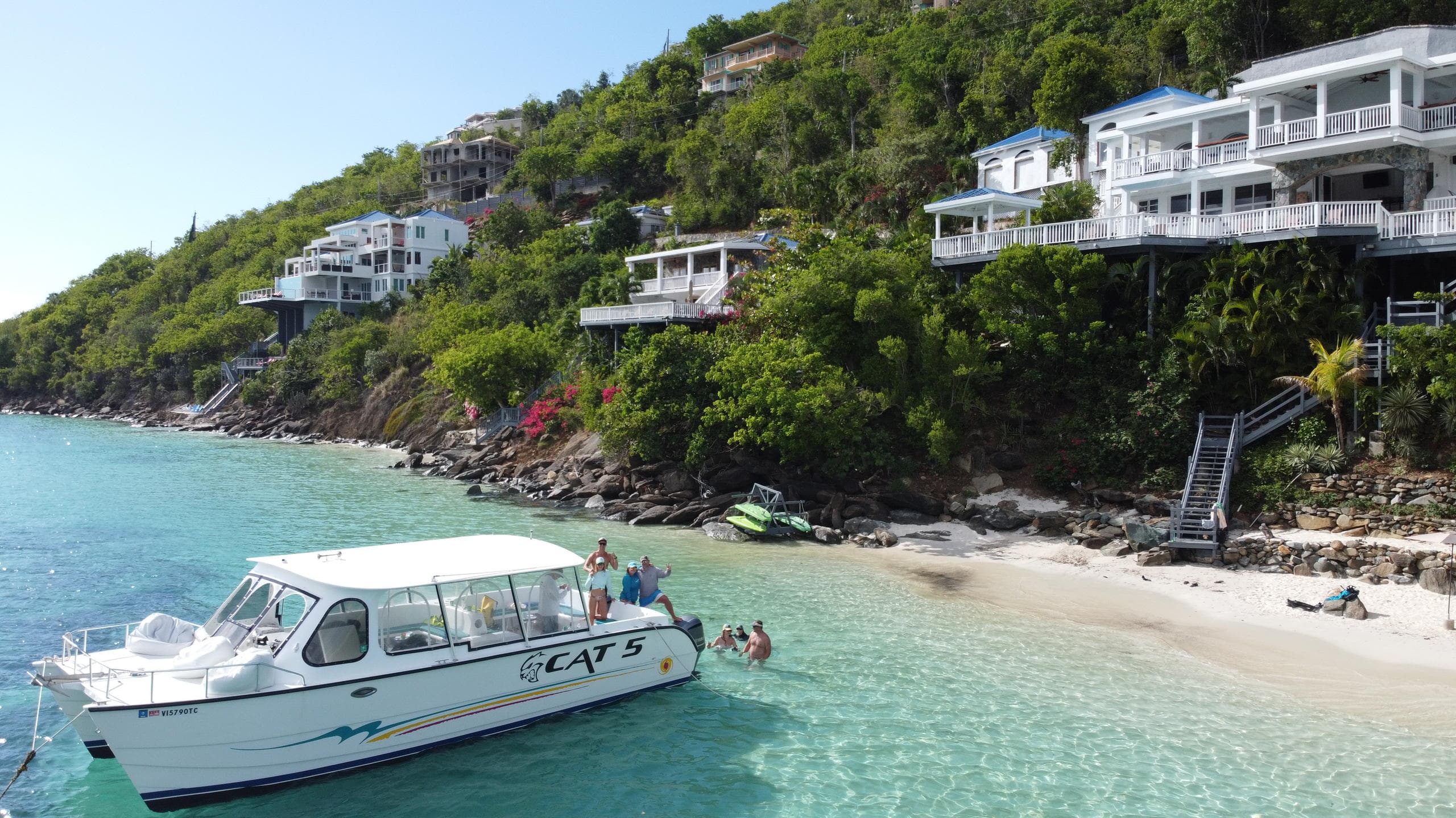 Coastal transfer boat moored by hillside villas on tropical shore