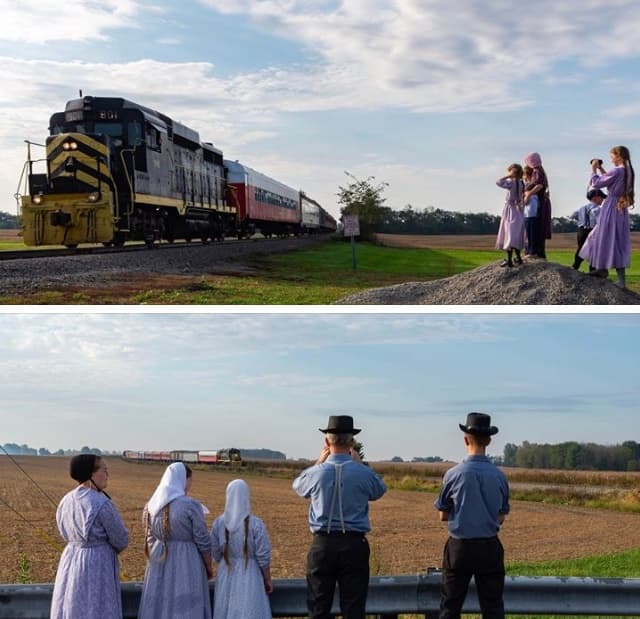 Amish families watching passing train across open farmland