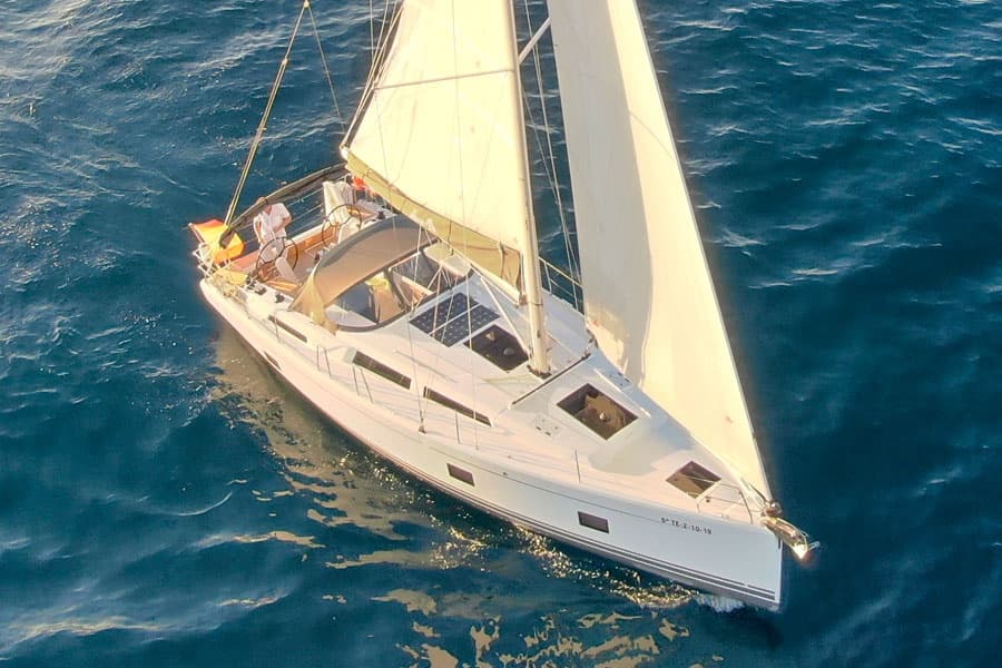 Aerial sailboat cruising open ocean under full white sail