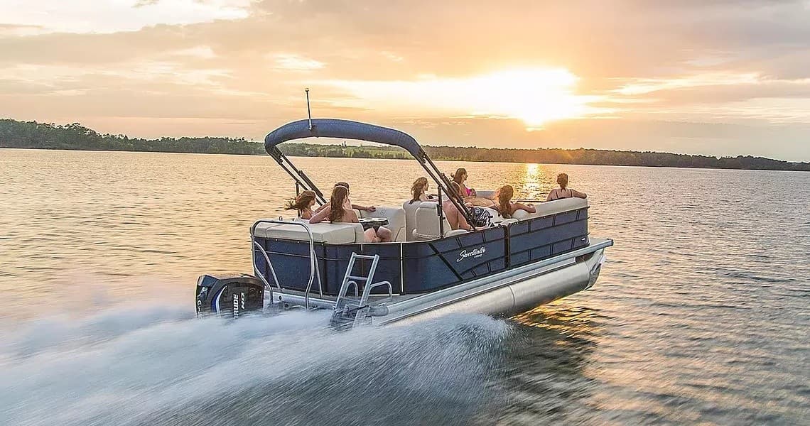 Pontoon boat cruising on lake at sunset, passengers enjoying ride