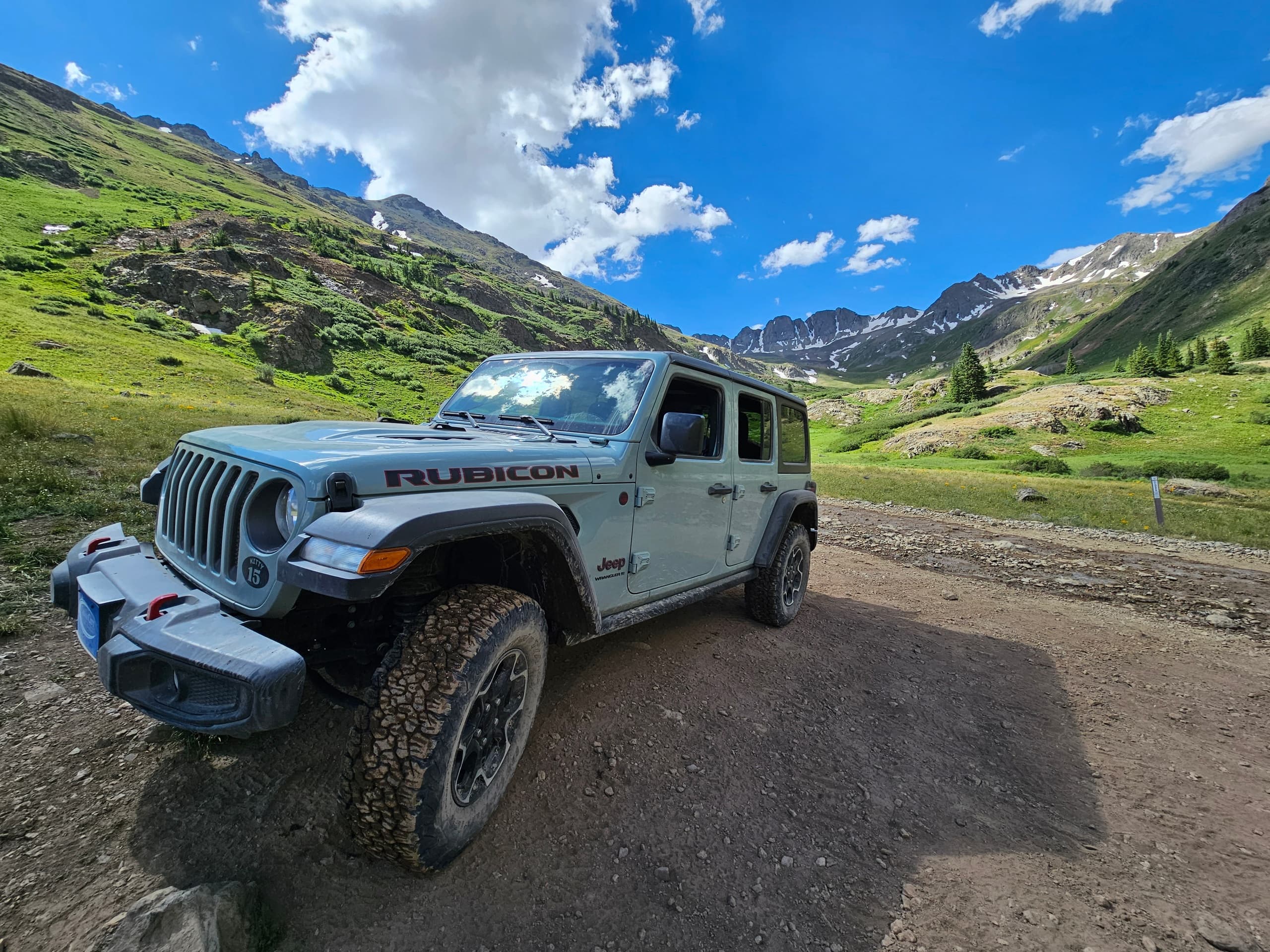 Jeep Rubicon driving on mountain dirt trail in alpine valley