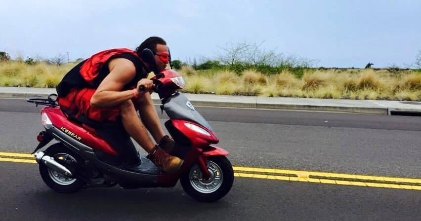 Solo scooter rider leaning into turn on coastal highway