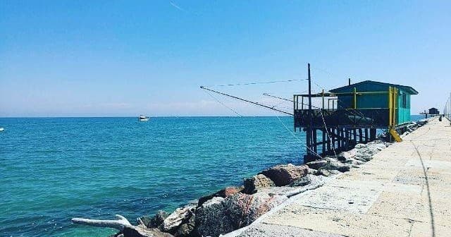 Fishing hut on rocky pier with turquoise sea and horizon