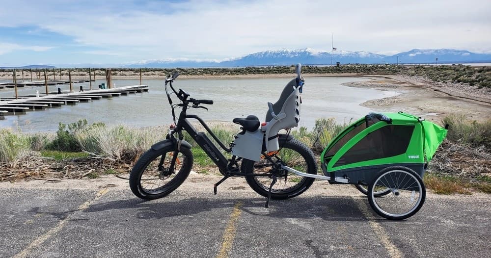 Cargo e-bike and green trailer parked near pier for beach touring
