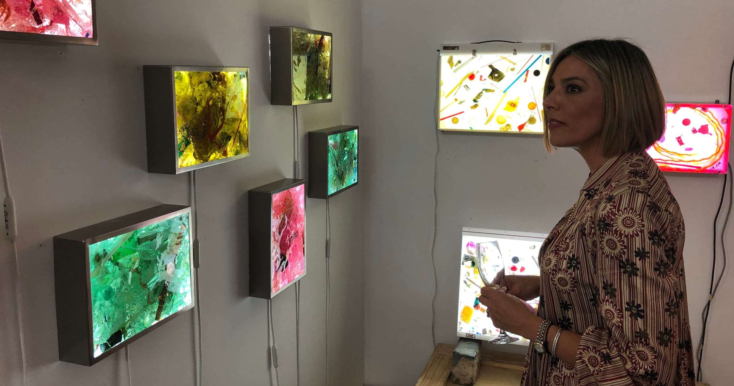 Visitor viewing illuminated mixed-media lightboxes in gallery