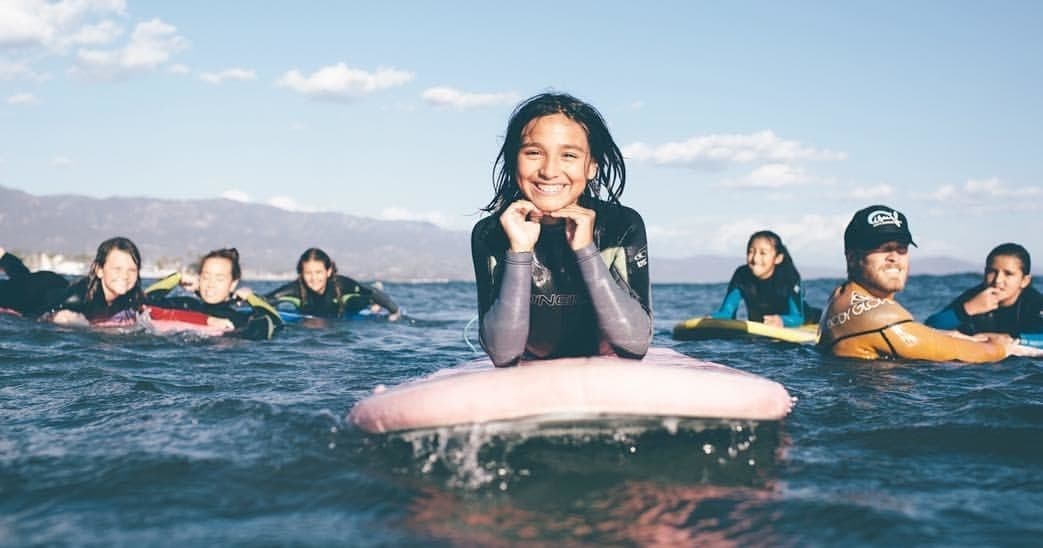 Group of beginner surfers floating on foam boards in the ocean