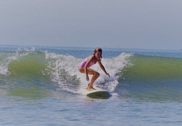 Young surfer riding clean green wave close to shore