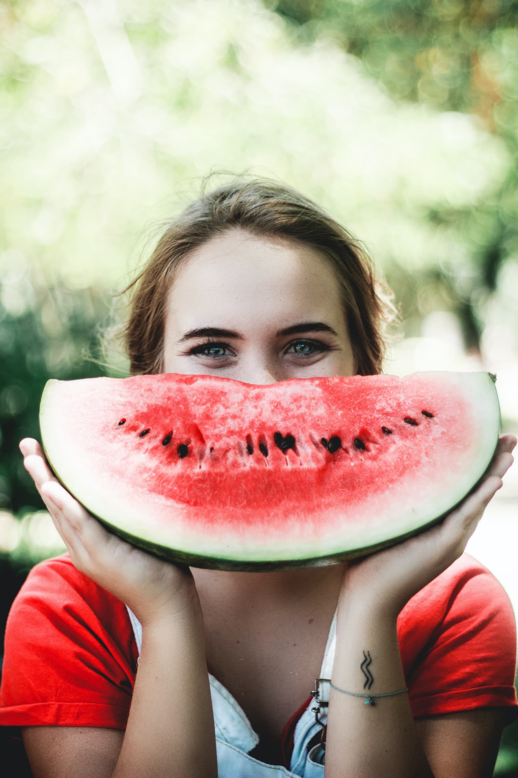 Woman holding watermelon slice smiling in park setting