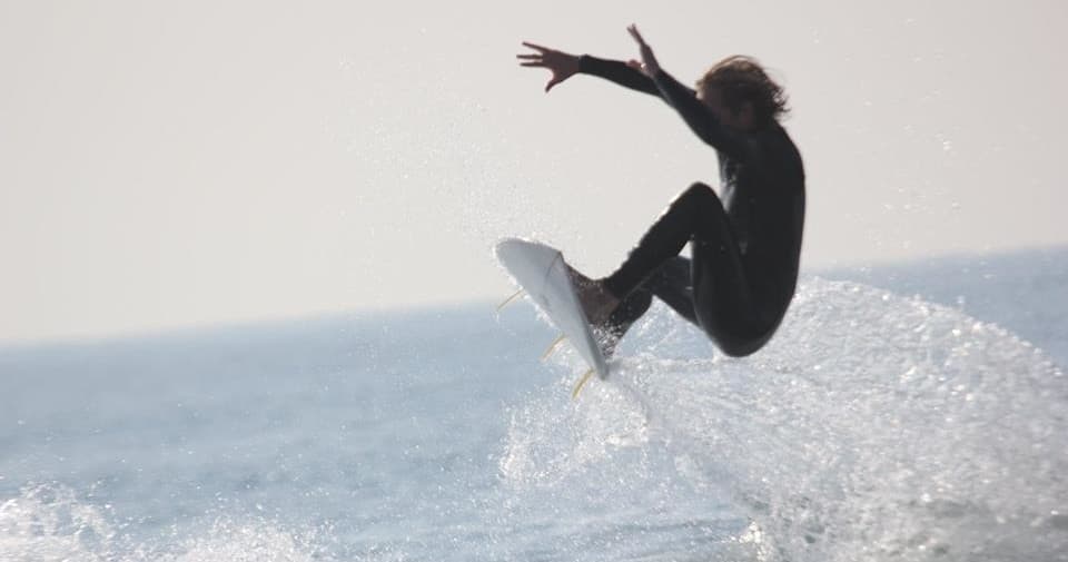 Surfer airborne over ocean waves, coastal California surfing