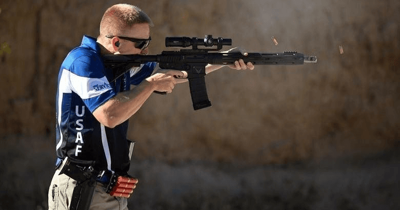 Shooter kneeling and firing rifle at indoor tactical range