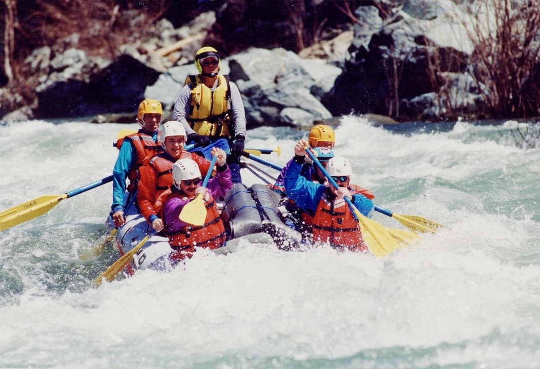 Whitewater rafters navigating rapids on a rocky mountain river