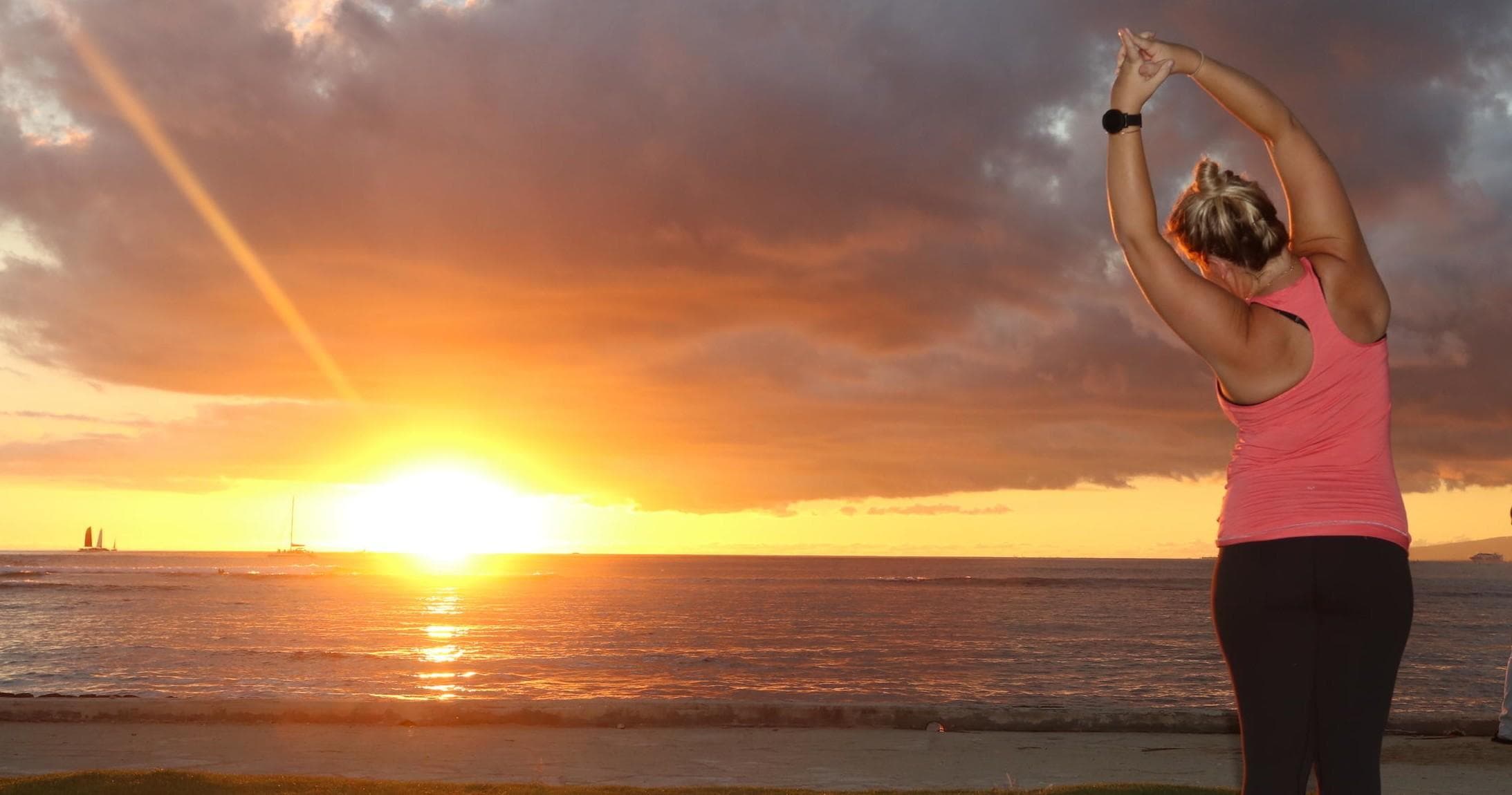 Woman stretching during beach sunset yoga by the ocean