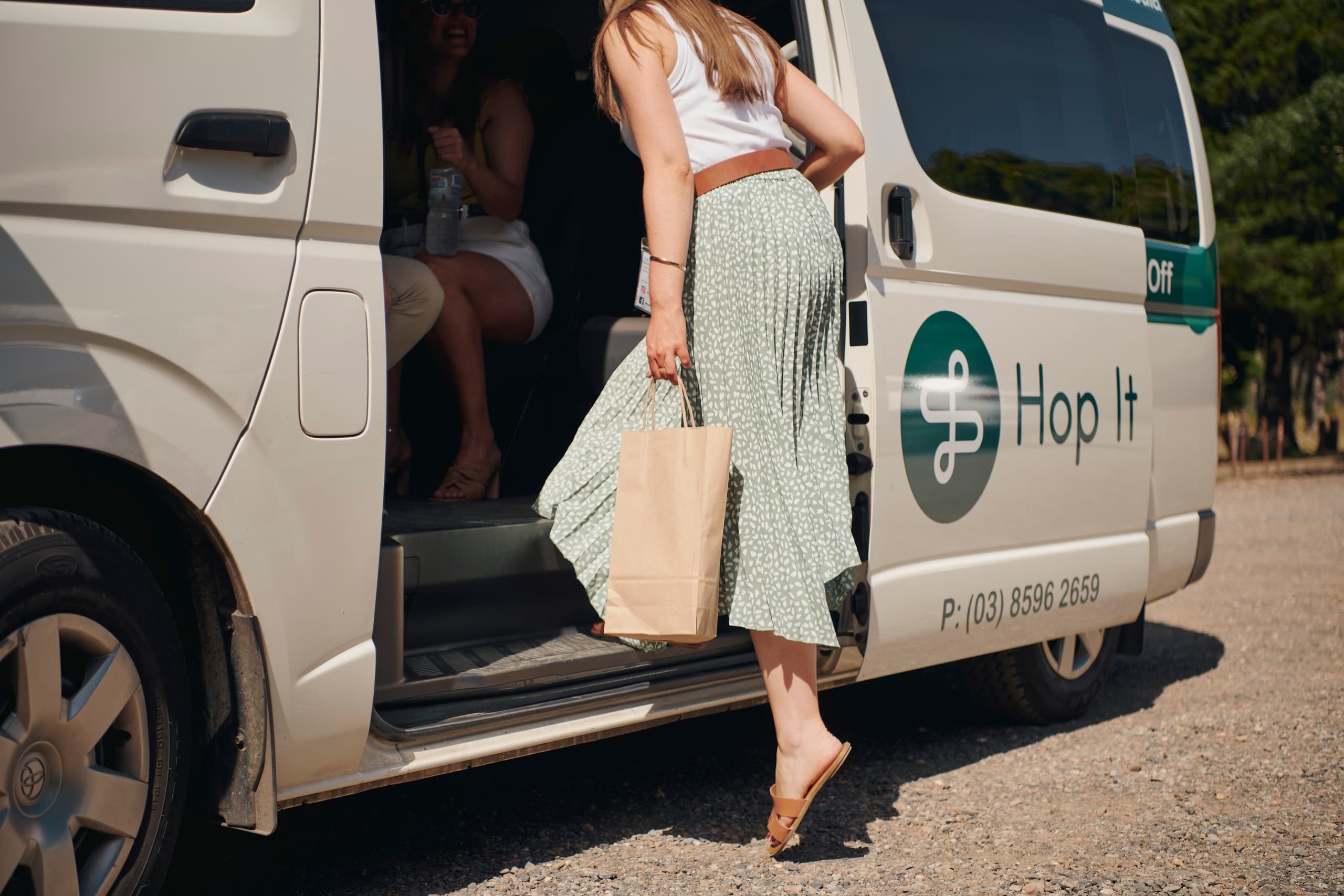 Passenger stepping into Hop It shuttle van at winery dropoff