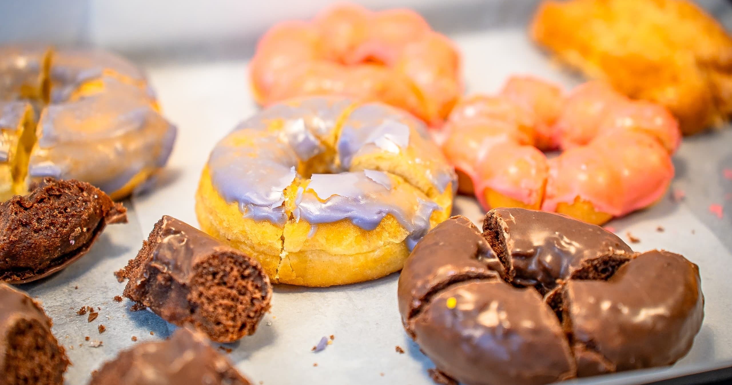 Assorted glazed donuts and pastries on indoor bakery display tray