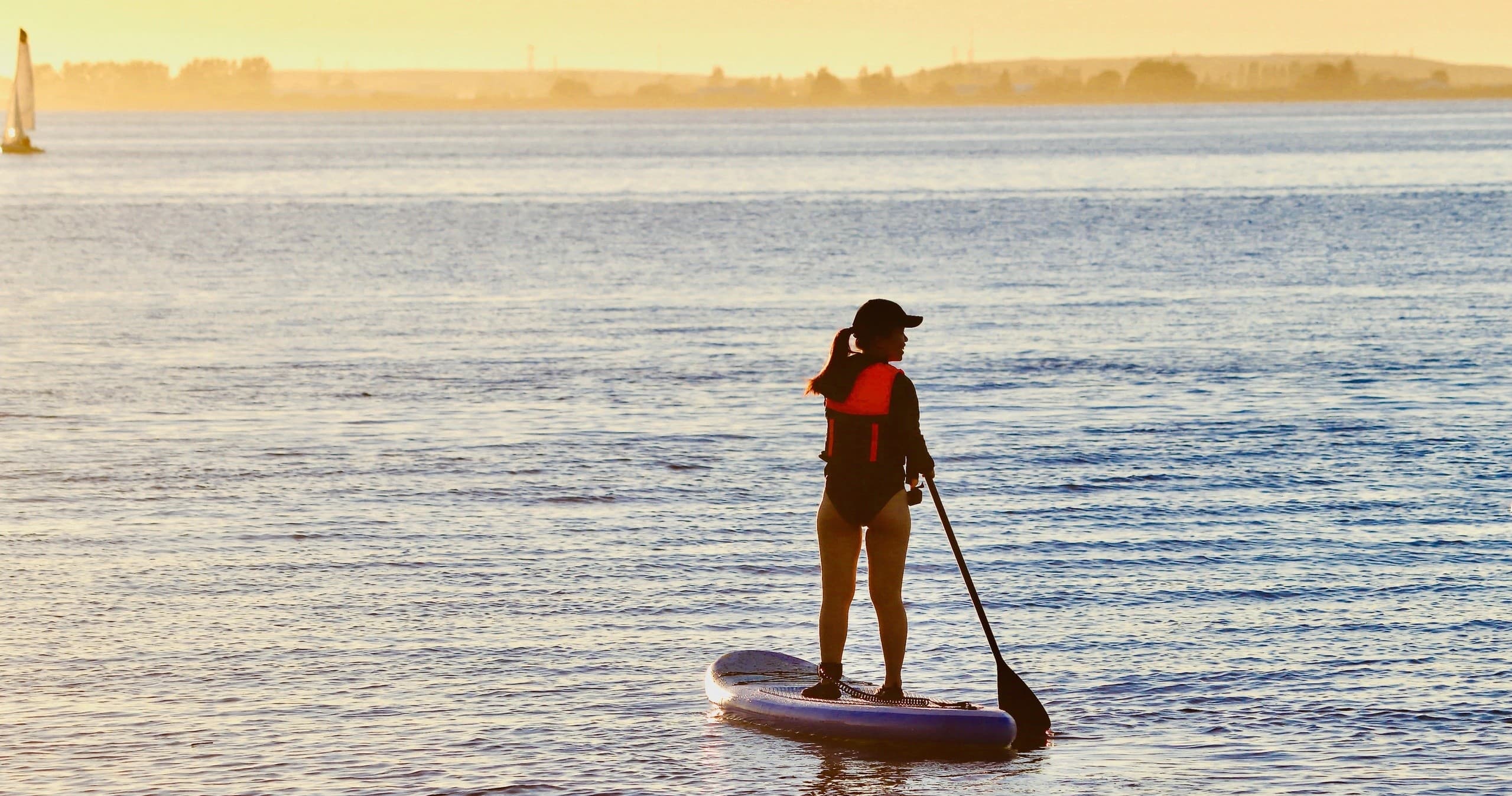 Stand-up paddleboarding at sunset on calm coastal waters